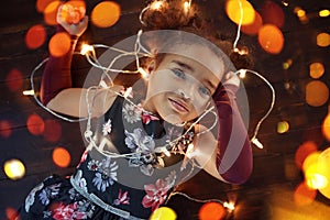 Beautiful little gir lying on the floor with garlands of lights