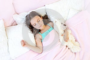 Beautiful little girl 5-6 years old sleeping in a bed with a Teddy bear