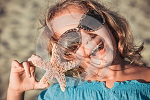 Beautiful little girl at the beach with starfish