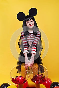 Beautiful little girl in black wig posing over bright yellow background