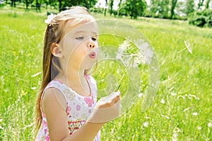 Beautiful little girl blowing dandelion