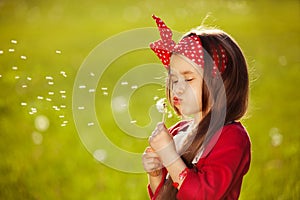 Beautiful little girl blowing dandelion