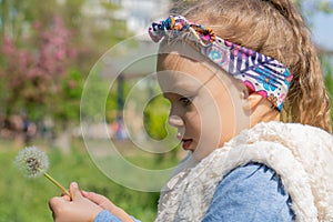 Beautiful little girl blowing dandelion. Cute girl on the medow.