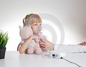 Beautiful little girl breathing into an inhaler for asthma and pneumonia at home. Treatment of diseases of the upper respiratory