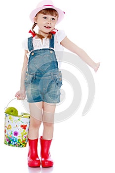 Beautiful little girl with a bucket of apples