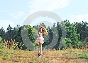 Beautiful little girl  dancing with flowers in sunny spring park. Happy cute kid having fun outdoors at sunset