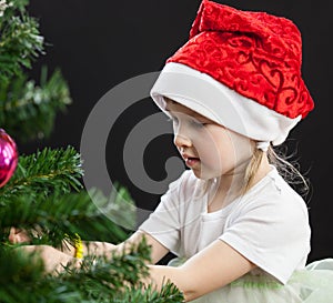 Beautiful little girl decorates the Christmas tree