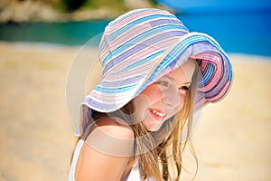 Beautiful little girl in dress and beach hat