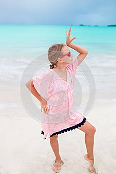 Beautiful little girl in dress at beach having fun. Funny girl enjoy summer vacation.