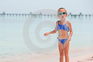 Beautiful little girl in dress at beach having fun. Funny girl enjoy summer vacation.