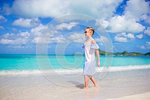 Beautiful little girl in dress at beach having fun. Happy girl enjoy summer vacation background the blue sky and