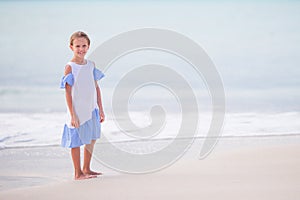 Beautiful little girl in dress at beach having fun. Happy girl enjoy summer vacation background the blue sky and