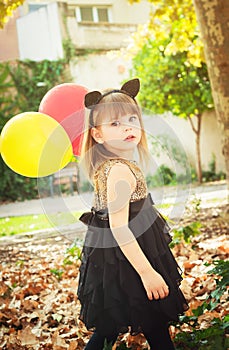 Beautiful little girl dressed as a cat with balloons in hands. Sweet smile, a tender look.