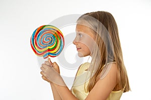 Beautiful little girl eating lollipop on white background