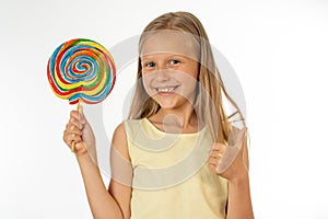 Beautiful little girl eating lollipop on white background