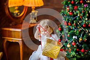 Beautiful little girl in a festive dress opens a gift