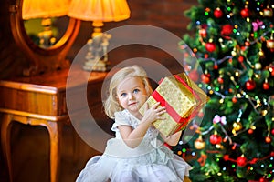 Beautiful little girl in a festive dress opens a gift