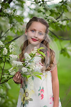 Beautiful little girl in the flowered garden with long hair