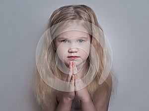 Beautiful little girl folded her hands in a prayerful gesture. photo
