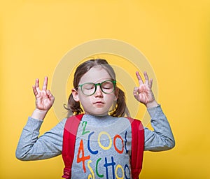 Beautiful little girl in glasses ready to go to school. Child relax and smiling with closed eyes. Kid doing meditation