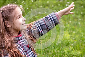 Beautiful little girl has fun outdoors in spring park with dandelion flower. Happy child.