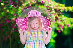 Beautiful little girl in a hat in blooming summer garden