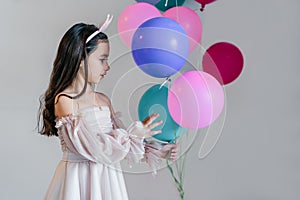A beautiful little girl having fun indoors with balloons during a birthday celebration.