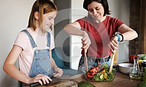 Beautiful Little Girl With Her Mother Cooking A Healthy Fresh Vegetable Salad