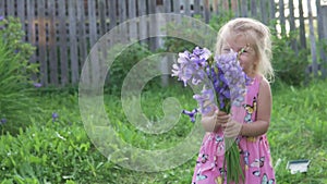 Beautiful little girl holding a bouquet of blue flowers and laughing