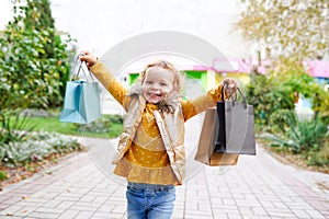 Beautiful little girl holding shopping colorful paper bags