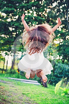 Beautiful little girl Is jumping outside at summer sunset
