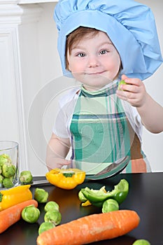 Beautiful little girl in kitchen apron and cap photo