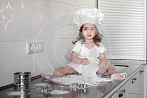 Beautiful little girl learns to cook a meal in the kitchen