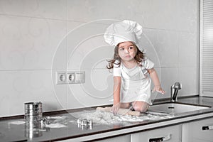 Beautiful little girl learns to cook a meal in the kitchen