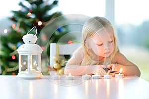 Beautiful little girl lighting a candle in white lantern