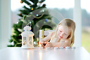 Beautiful little girl lighting a candle in white lantern