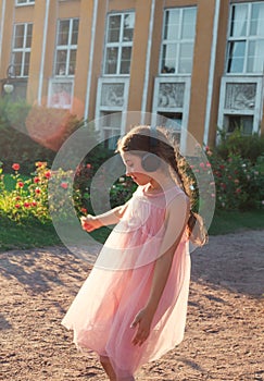 Beautiful little girl listen to music in sunny spring park. Happy cute kid having fun outdoors at sunset. Soft focused