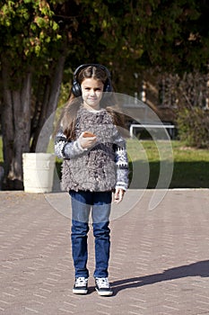 Beautiful little girl listening to music on headphones