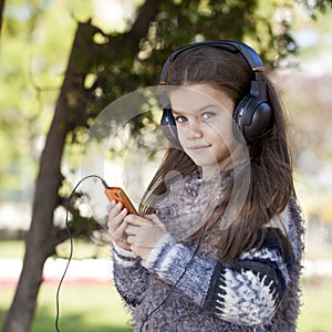 Beautiful little girl listening to music on headphones