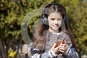 Beautiful little girl listening to music on headphones