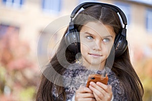 Beautiful little girl listening to music on headphones