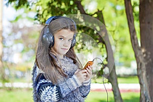 Beautiful little girl listening to music on headphones