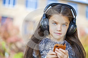 Beautiful little girl listening to music on headphones