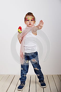 Beautiful little girl with lollipop with painted face showing stop hand in children love sweet and sugar concept.