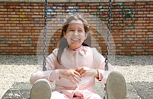 Beautiful little girl with long brown hair plays with swing in p