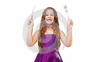 Beautiful little girl with long hair in evening dress, portrait emotionally posing with a knife and fork, isolated