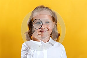 Beautiful little girl looking through a magnifying glass. The concept of education, school, research, search