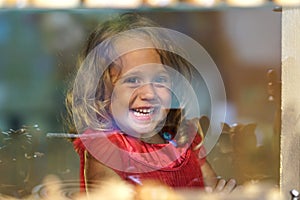 Beautiful little girl looks in the window of a shop in OIA, and makes funny faces