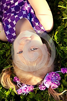 Beautiful little girl lying on the grass in the park. Smiling ch