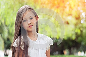 Beautiful little girl in the park, with long hair and and a sweet, gentle look. Happy childhood concept.
